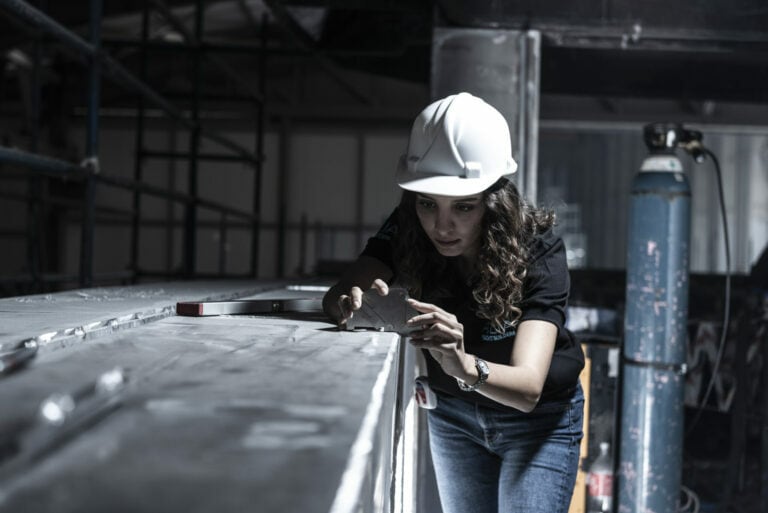 Lady with hard hat measuring the angle of the fabrication